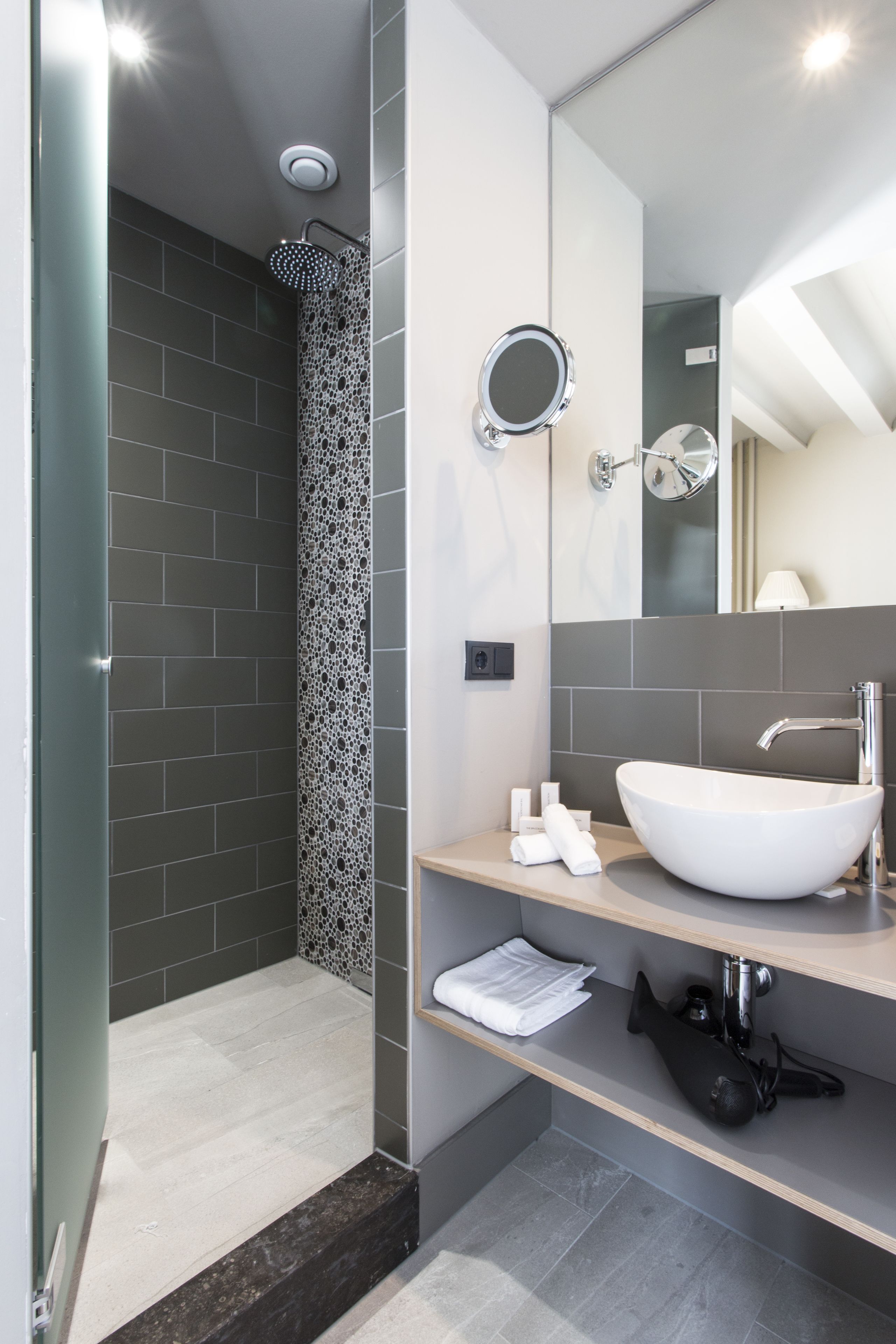 Een moderne badkamer met een douche, wastafel en spiegel.