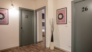 Un pasillo con puertas numeradas 22 y 26, suelo de madera y discos de vinilo enmarcados en las paredes.