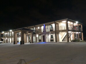 A multi-story motel with a central entrance, a covered parking area, and a staircase leading to the upper floor.