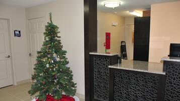 Un árbol de Navidad en el vestíbulo de un hotel, con una recepción y una puerta que indica 'Men's Restroom'.