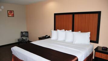 A hotel room with a large bed, a nightstand, a chair, and a wooden headboard.