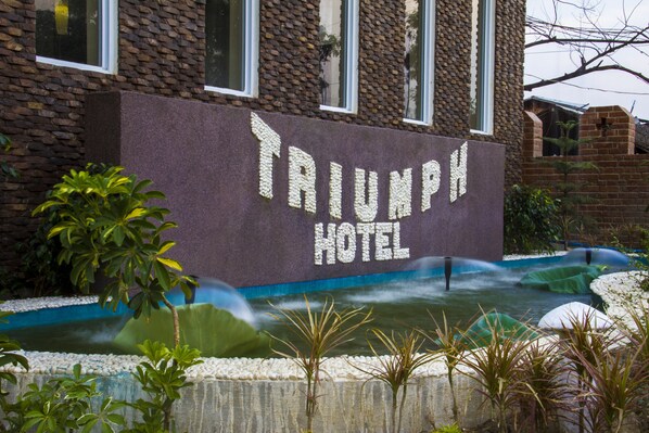 A brick building with a sign that reads "TRIUMPH HOTEL."