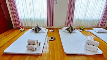 A hotel room with two beds, each with a pillow and a rolled towel.