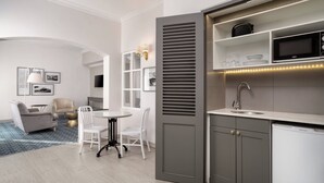 A modern kitchen with built-in appliances, a dining area with a round table and chairs, and a living room with a sofa and armchairs. - Protea Hotel by Marriott Cape Town Mowbray (Cape Town)