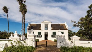 A white colonial-style building with a symmetrical facade, a central entrance, and a thatched roof. - Protea Hotel by Marriott Cape Town Mowbray (Cape Town)