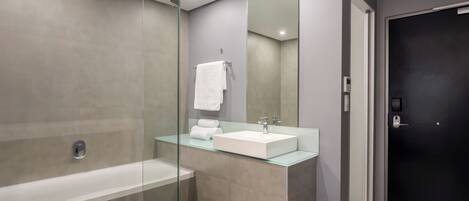 Une salle de bain moderne avec une douche à parois de verre, un lavabo blanc et une porte noire.