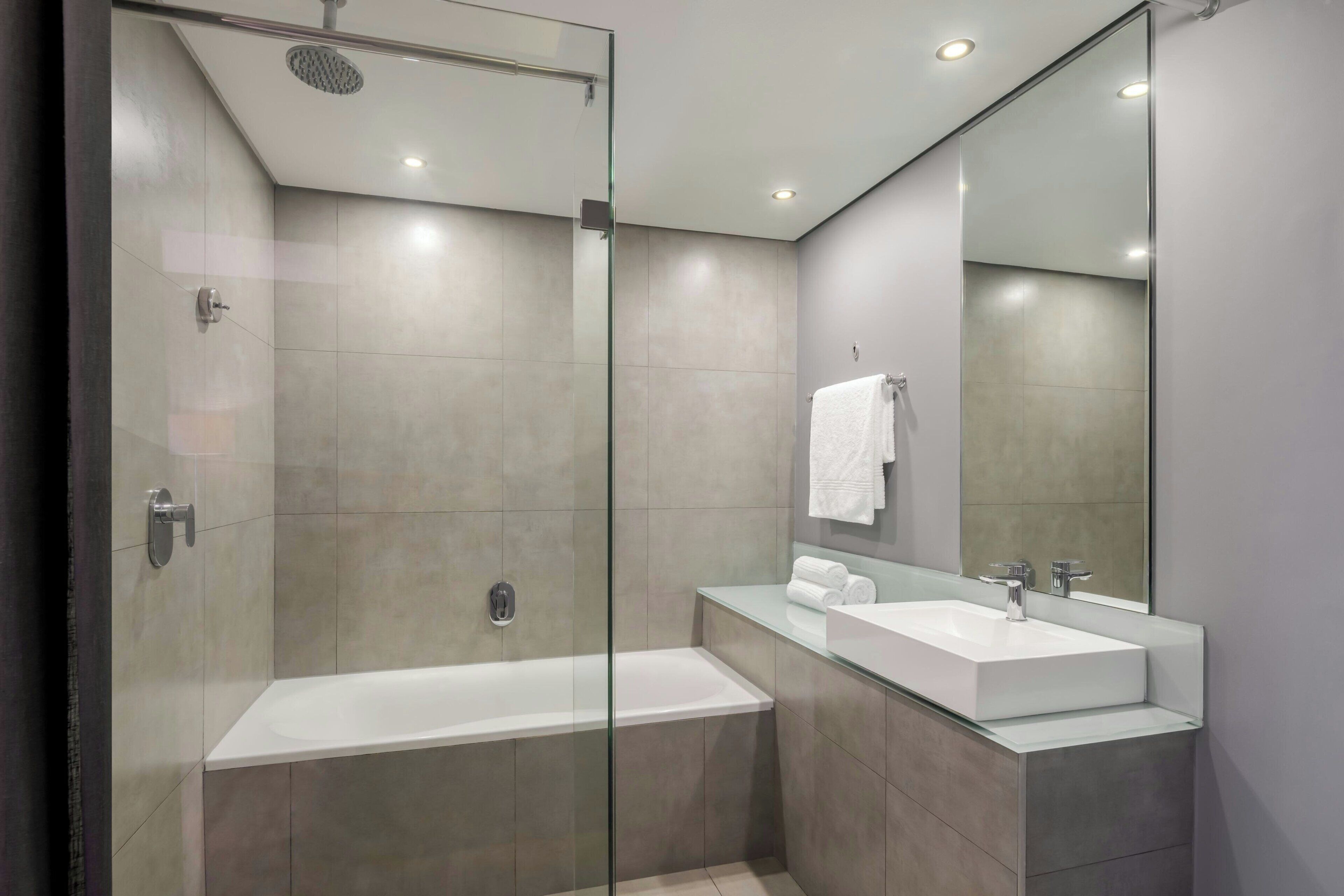 Une salle de bain moderne dotée d’une douche à parois de verre, d’une baignoire sur pied et d’un meuble-lavabo avec un miroir.