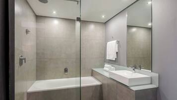 Un baño moderno con ducha de vidrio, bañera independiente y tocador con espejo.
