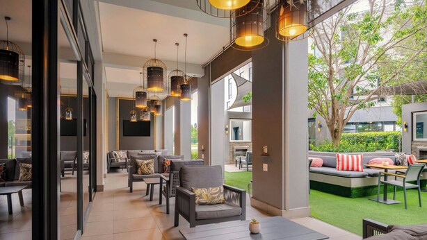 An indoor-outdoor living area with seating, a fireplace, and a view of the outdoors. - Protea Hotel Fire & Ice by Marriott Pretoria Menlyn (Pretoria)