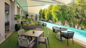 An outdoor patio with tables and chairs, a pool, and greenery. - Protea Hotel Fire & Ice by Marriott Pretoria Menlyn (Pretoria)