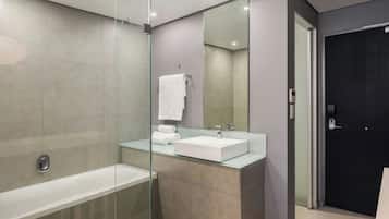Un baño moderno con ducha de vidrio, un lavamanos blanco y una puerta oscura.