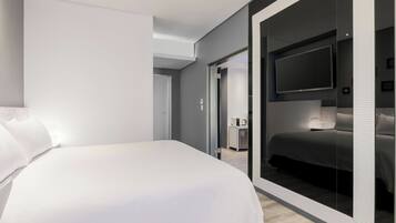 Una habitación de hotel moderna con una cama grande, un televisor y un espejo.