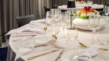 Una mesa vestida con manteles blancos, cubiertos dorados y copas de cristal.