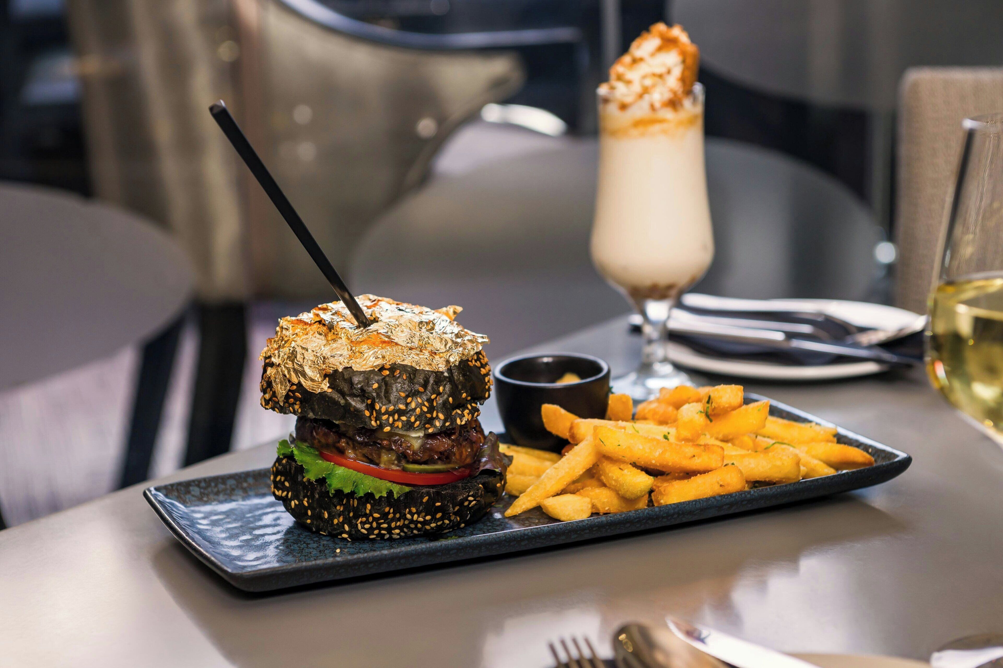 En måltid som består av en hamburgare, pommes frites och en dessertdryck, serverat på ett fat.
