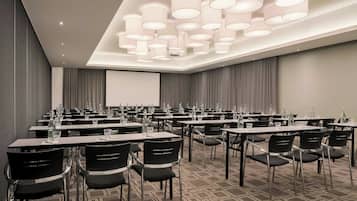 A conference room with tables, chairs, and a projector screen.