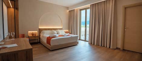 A hotel room with a bed, a desk, a mirror, and a view of the outdoors.