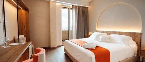 Une chambre d’hôtel équipée d’un lit, d’un bureau, d’une chaise, d’une fenêtre avec des rideaux et d’une lampe fixée au mur.
