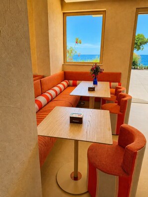 A seating area with a view of the sea, featuring orange and white striped cushions, a small table with a vase, and a wooden floor. - Hotel Boutique Terracotta Sapri (Sapri)