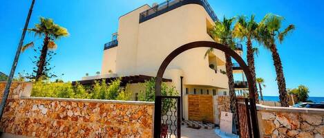 Un edificio moderno con fachada curva, entrada de pared de piedra y palmeras.