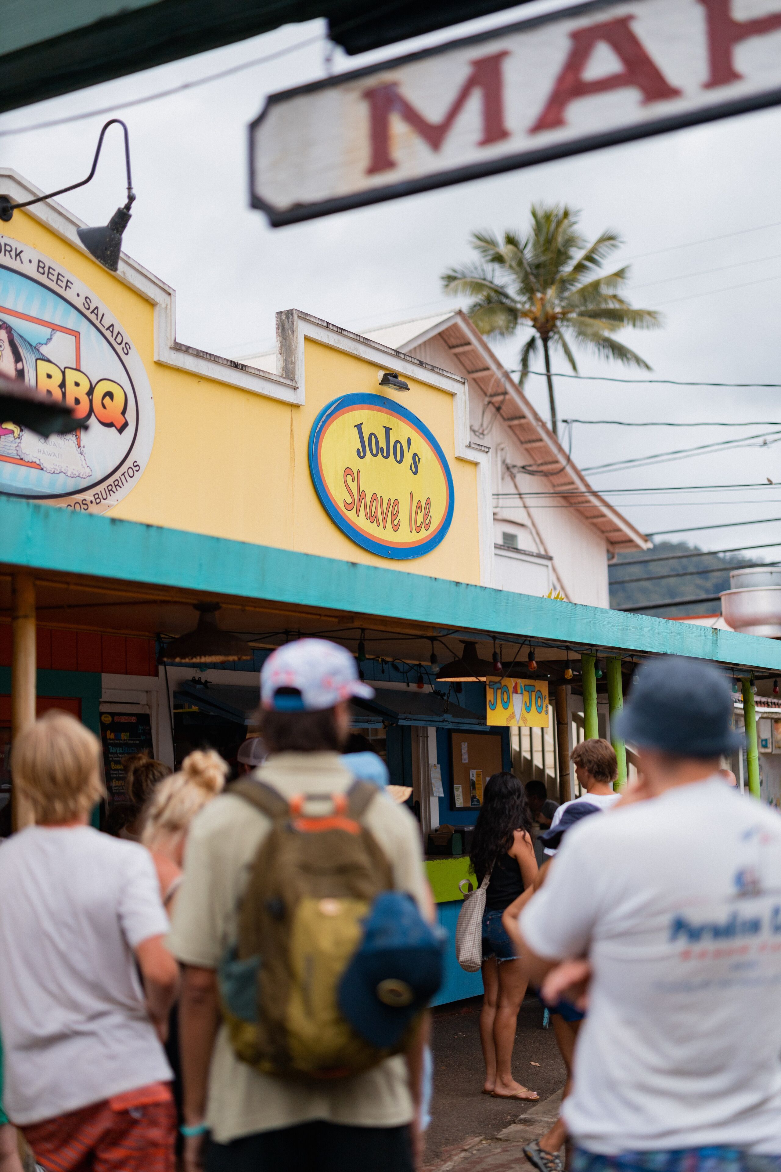 Un restaurant appelé « Jolo’s Shave Ice », avec une enseigne et une foule de personnes devant.