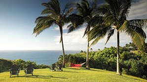 A grassy area with two Adirondack chairs, a small table, and a hammock. - The Cliffs at Princeville (Princeville)