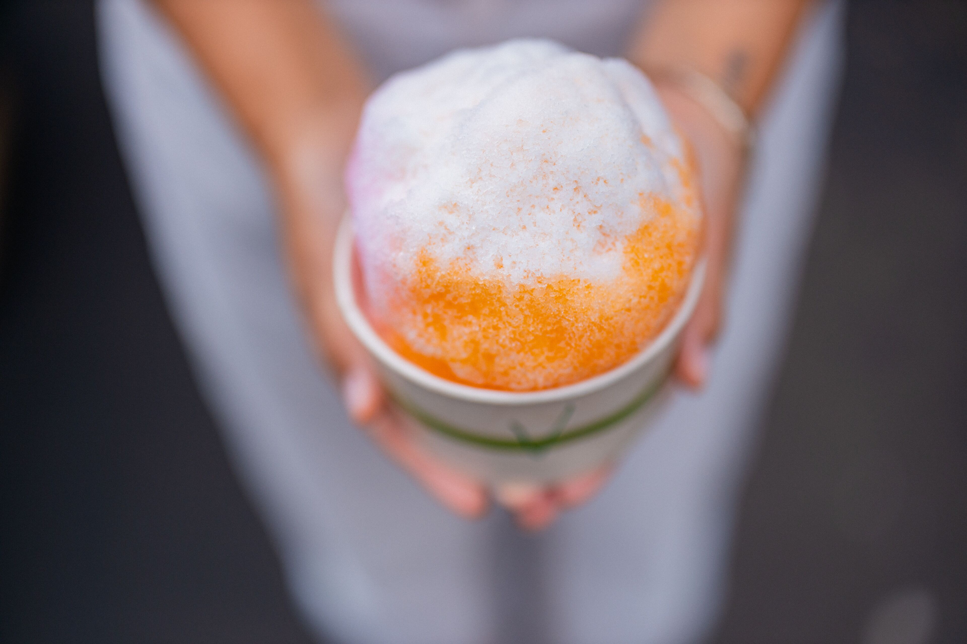 A person holding a cup with a layered dessert.
