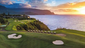 A golf course with bunkers and a view of the ocean at sunset. - The Cliffs at Princeville (Princeville)