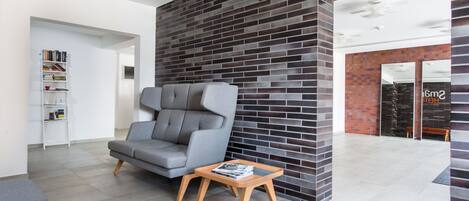 Una sala de estar moderna con un sofá gris, una mesa de centro de madera y una pared de ladrillo decorativa.