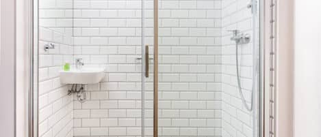 A bathroom with white subway tiles, a glass shower enclosure, and a sink with a faucet.