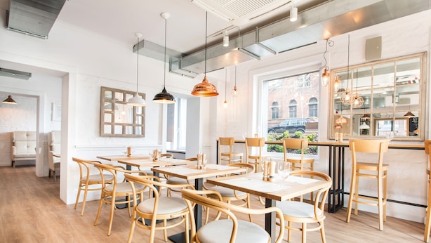 A modern dining area with wooden tables and chairs, pendant lighting, and a view of the outside. - Smart Hotel Garnizon (Gdansk)
