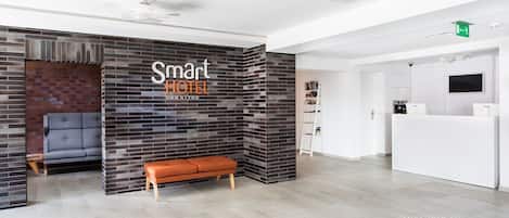 A reception area with a modern design, featuring a reception desk, a seating area with a bench, and a wall with a brick pattern.