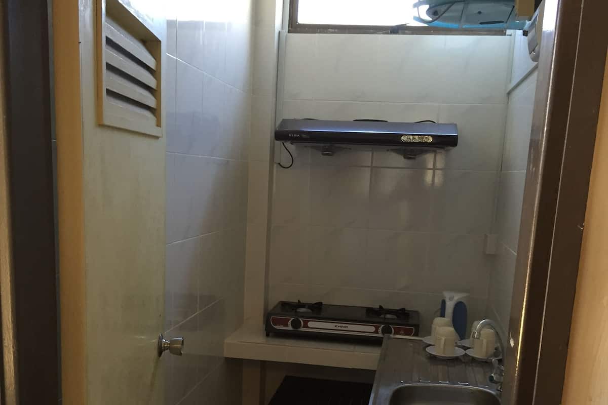 Una cocina compacta con estufa a gas, lavamanos y un ventanal pequeño.