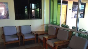 A seating area with wooden chairs and tables, a green door, and a window with a view of the outside. - Seapark Condotel (Kota Kinabalu)