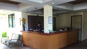 A reception desk with a wooden counter, a chair, and a vase with sunflowers. - Seapark Condotel (Kota Kinabalu)