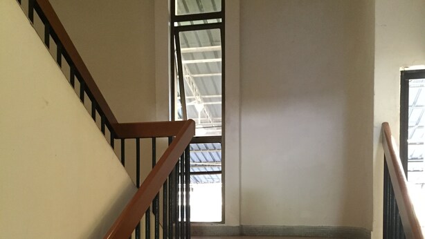 A staircase with tiled steps and wooden handrails, leading to a room with a window. - Seapark Condotel (Kota Kinabalu)
