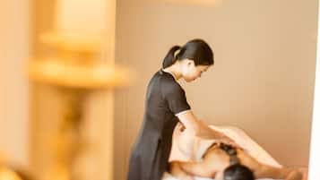 A massage therapy session in a room with a massage table, a massage therapist, and a lamp.