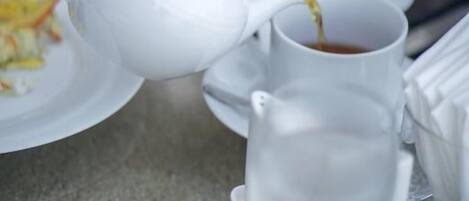 A white teapot being poured into a white cup.