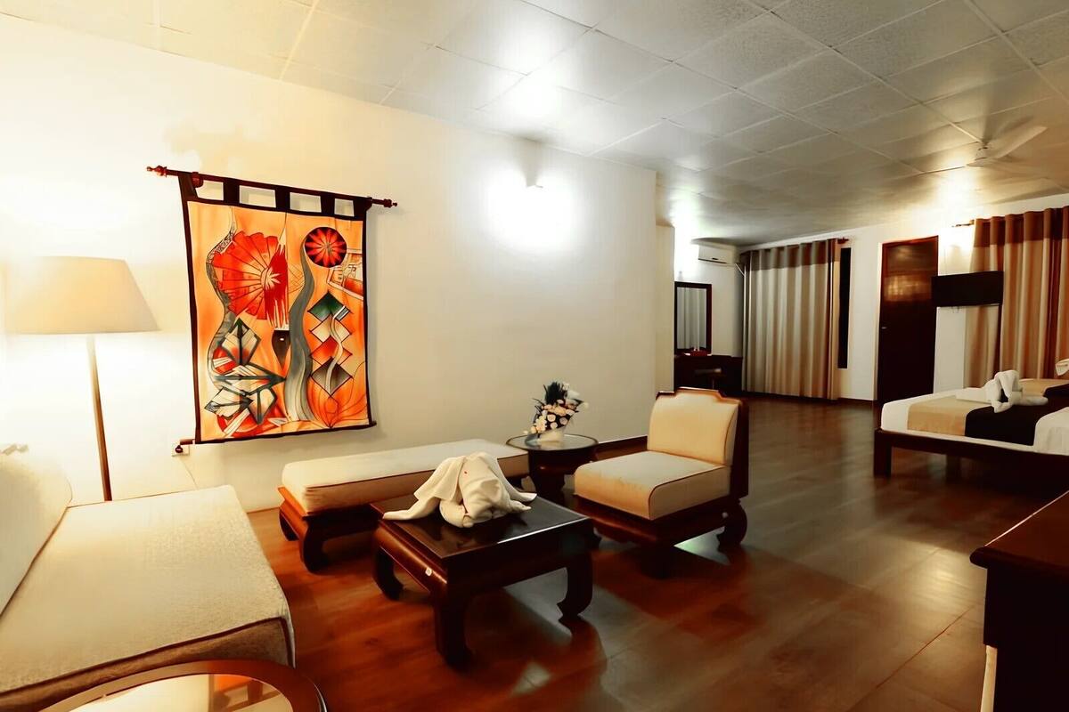 Une chambre d’hôtel avec un grand tableau, un canapé, un fauteuil, une petite table et un lit.