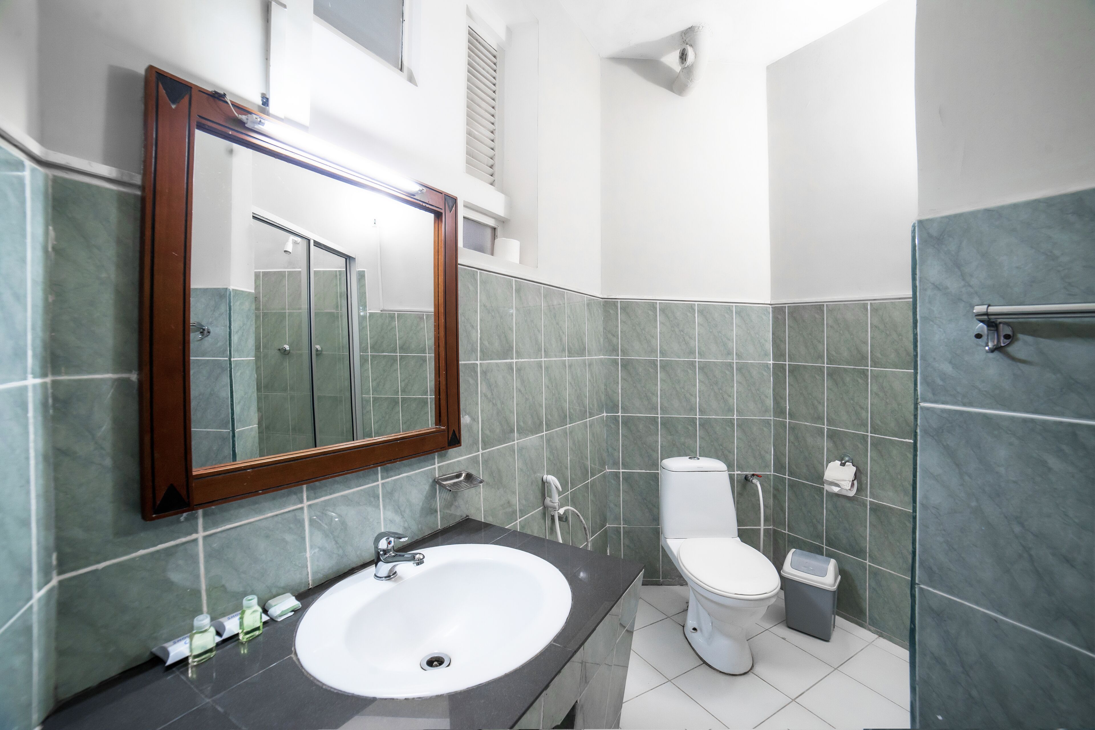 A modern bathroom with a large mirror, white sink, and toilet.