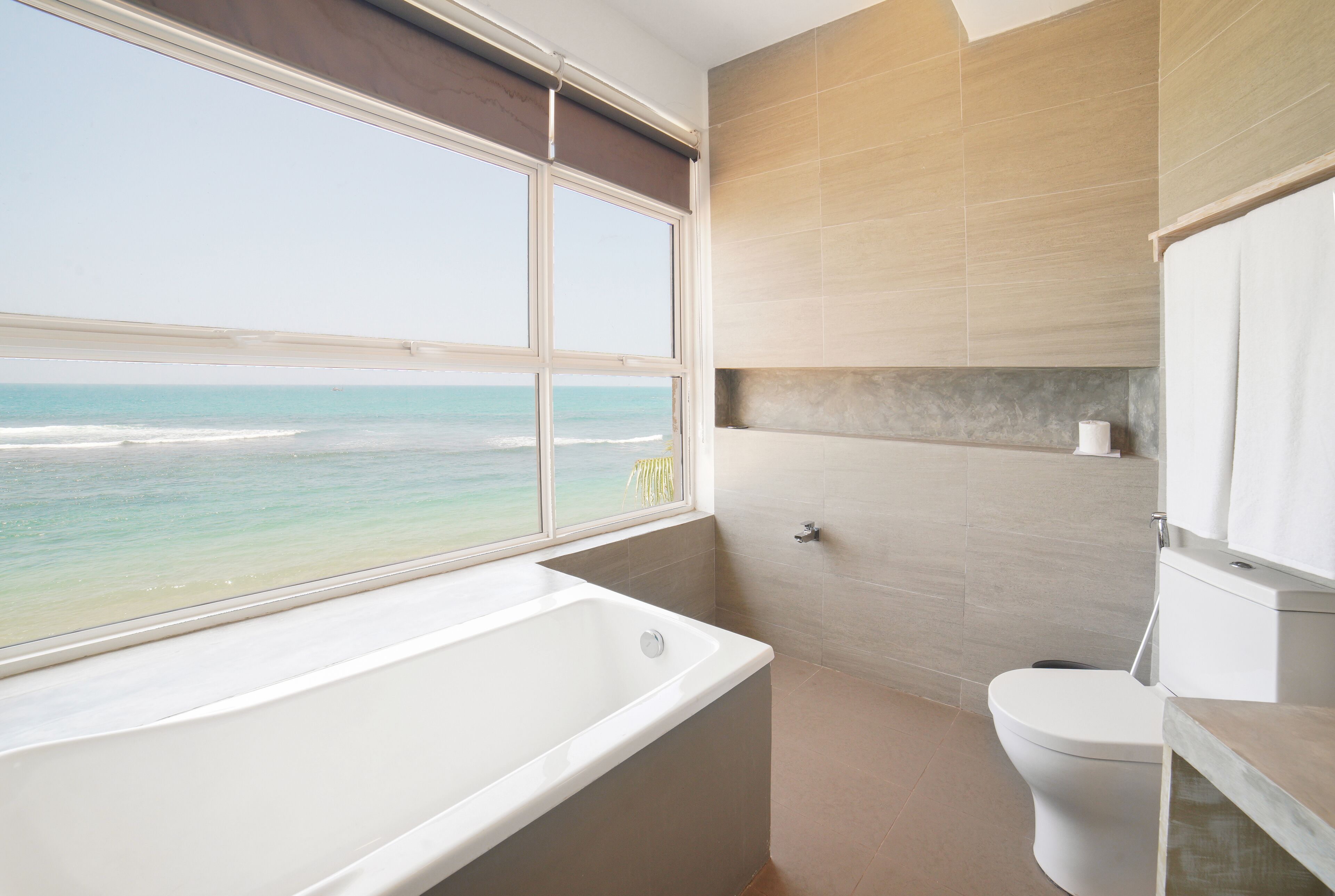 Un baño con bañera, inodoro y vista al océano.