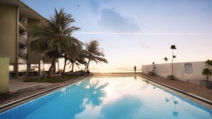 Una piscina con palmeras y vista al océano.