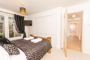 A bedroom with a bed, a TV mounted on the wall, and a window with curtains.