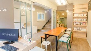 Interior moderno de un hostal con un escritorio de madera, una computadora, una escalera y una estantería con revistas.