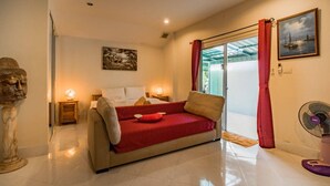 Un dormitorio con una cama, una manta roja, un ventilador y una ventana con cortinas rojas.
