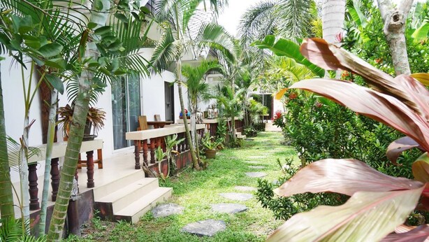 Un jardín tropical con un sendero de piedra que lleva a una escalera de madera.