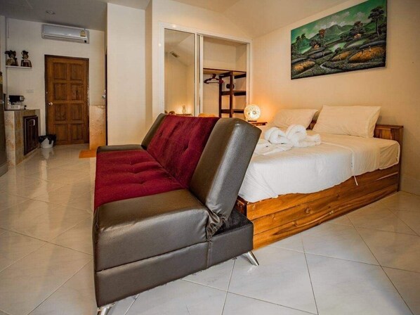 Un dormitorio con cama, sofá, armario de madera y un cuadro en la pared.