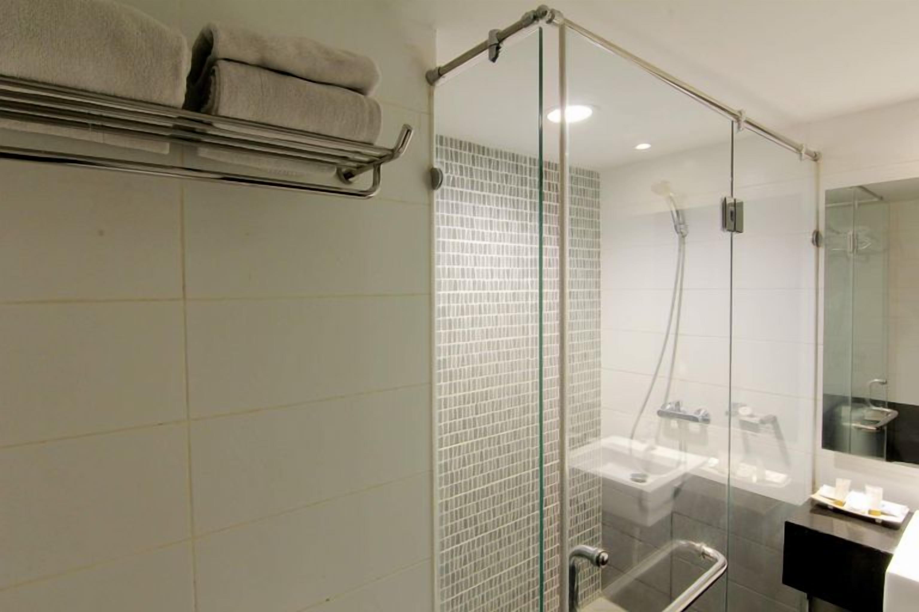 A modern bathroom with a glass shower enclosure, a towel rack, and a sink.