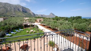 Terraço com vista para montanhas e o mar, mobiliário de exterior e um jardim.