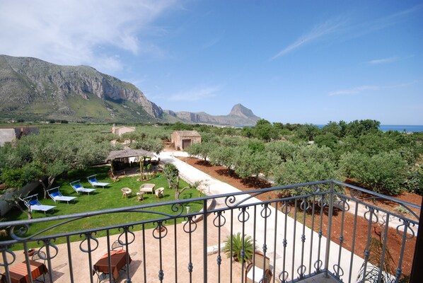 Une terrasse offrant une vue sur les montagnes et la mer, des sièges extérieurs et un jardin.