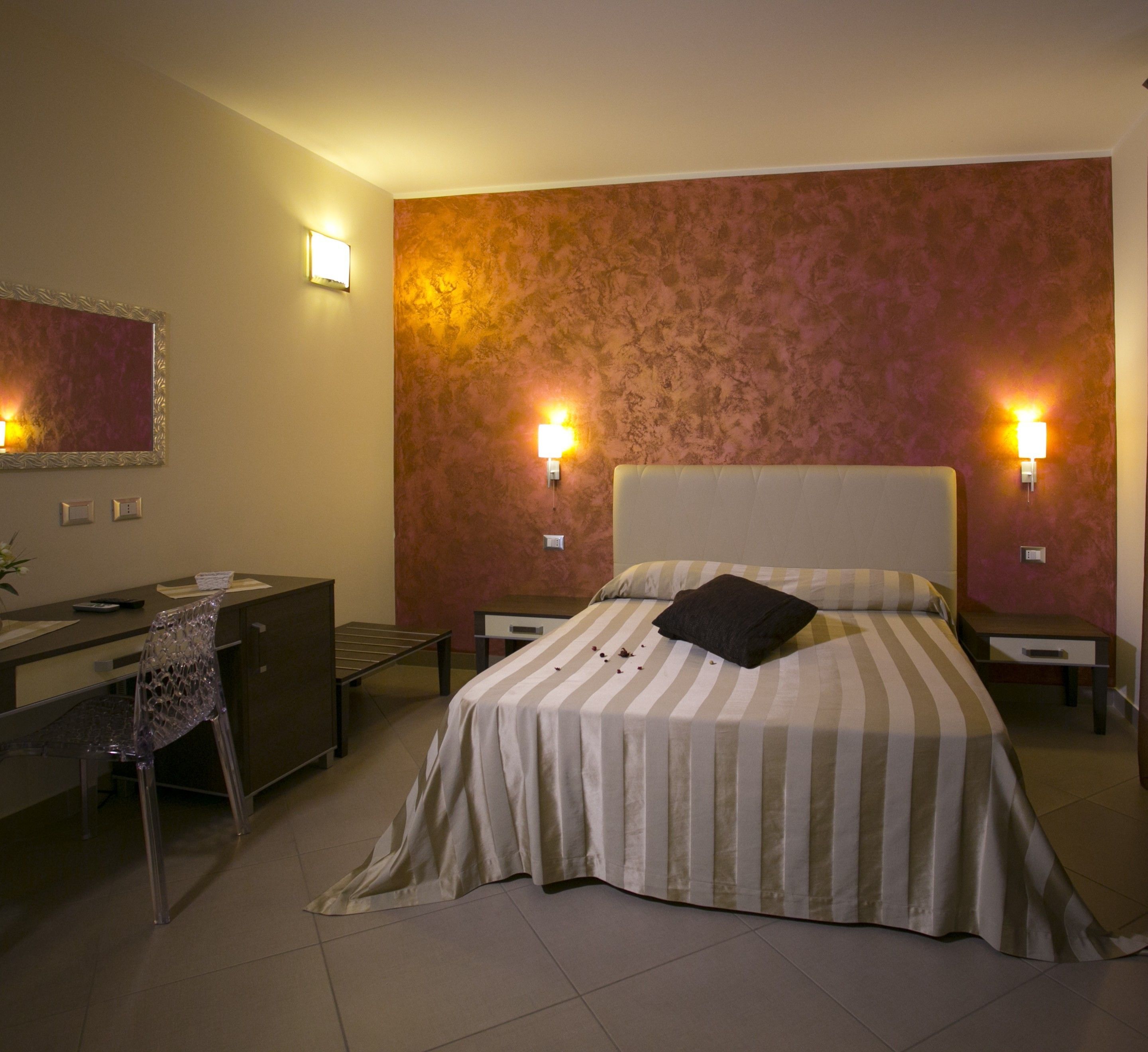 A hotel room with a bed, a desk, a chair, and two bedside lamps.